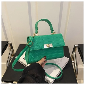 Détail d'un sac à main vert fluo gaufré crocodile avec un fermoir tournant en métal doré