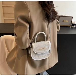 Close-up of silver pleated crossbody saddle bag with metallic handle and golden trim detail