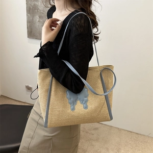Minimalist straw tote bag with light blue handles and butterfly decoration for summer