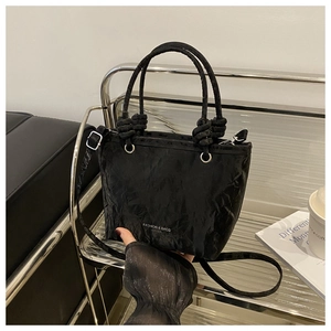 Vue détaillée de l'anneau en métal argenté et de l'anse nouée sur le sac seau en cuir noir