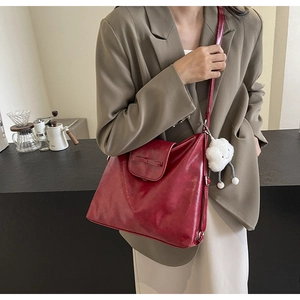 Detail of burgundy leather tote bag with bow flap and white cloud charm on side