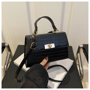 Détail de la texture motif crocodile noir et du fermoir tournant en métal doré du sac