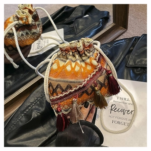 Détail du sac seau bohème tissé avec motifs géométriques et pendentifs à pampilles colorés