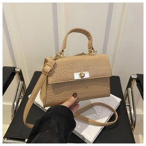 Détail du sac beige à motif crocodile avec fermoir rotatif rectangulaire doré chic
