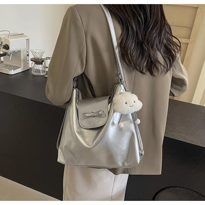 Close-up of metallic silver tote bag with bow detail and white cloud plush charm