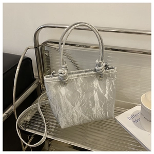 Détail d'un sac à main plissé gris argenté avec texture métallique et anse nouée