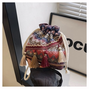 Gros plan détaillé du sac seau tissé ethnique avec motifs colorés et pompons