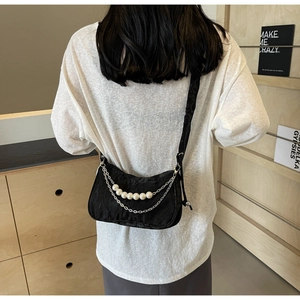 Détail du sac bandoulière en nylon noir avec plis texturés, perles et chaînes argentées