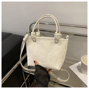 Détail du sac seau à motif marbré crème avec poignées à nœuds et bandoulière réglable