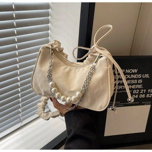 Détail du sac croissant plissé crème avec chaîne en perles et design à cordon coulissant