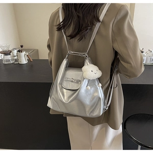 Detail of silver metallic tote bag with bow accent and white cloud plush charm in cafe setting