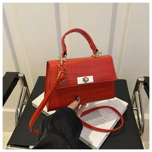 Détail du sac à main rouge à motif crocodile avec fermoir doré et bandoulière