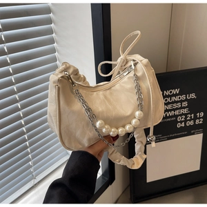Détail du sac croissant crème avec chaîne en perles et métal argenté sur cuir texturé