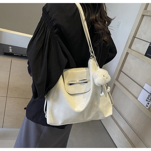 Creamy white tote bag with black bow detail and plush cloud charm on a model side view
