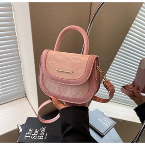 Detail of light pink saddle bag featuring marble texture flap and gold metal bar accent