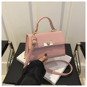 Détail du sac rose avec texture crocodile et fermoir rotatif en métal doré élégant