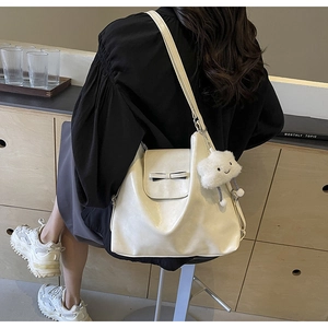 Detailed view of cream white tote bag with bow decoration and cloud charm on model