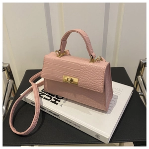 Détail de la texture cuir croco rose et du fermoir doré rotatif sur le petit sac à main