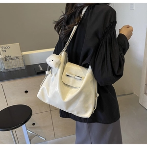 Detail view of cream white tote bag with bow decoration and cute plush sheep charm