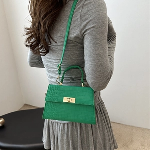 Sac à main vintage vert effet crocodile avec fermoir doré porté sur l'épaule