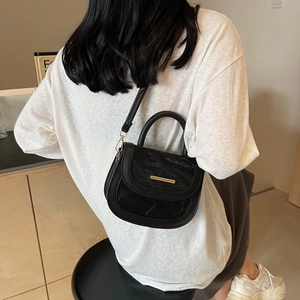 Black vintage saddle bag with marble texture flap and gold buckle on a model
