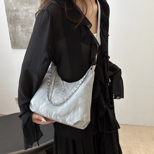 Borsa tote metallizzata argento a pieghe con catena su abito nero