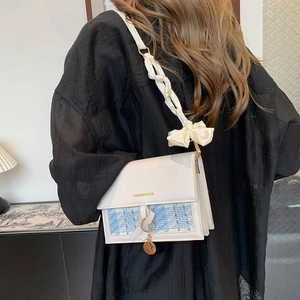 Chic beige crossbody bag with blue plaid texture and silk bow strap worn by a model