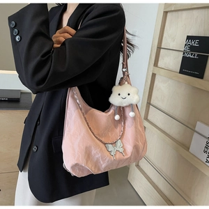 Detailed view of pink crescent bag with silver butterfly charm and plush cloud pendant