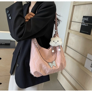 Detail view of pink pleated tote bag with silver butterfly charm and cloud doll accessory