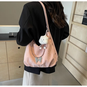 Detail of pink pleated tote bag with silver butterfly chain and plush cloud charm