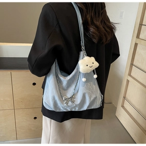 Detail of light blue hobo bag with silver butterfly chain and plush cloud charm