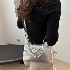 Silver square crossbody bag with metallic texture and butterfly bow buckle on model