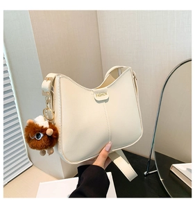 Detail of beige PU leather shoulder bag with FASHION metal plate and brown plush pendant