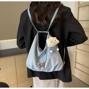 Detail view of light blue wrinkled nylon backpack with butterfly and cloud plush charms