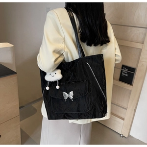 Detail view of black pleated tote bag with butterfly metal clasp and cloud pendant