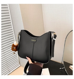 Detail of black matte shoulder bag with golden text and cute plush animal charm