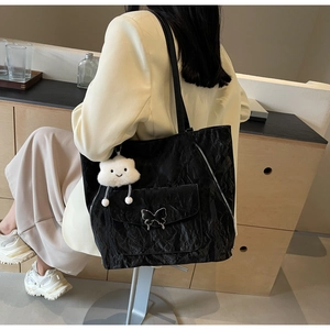 Detail showing black pleated tote bag with silver butterfly buckle and cloud charm
