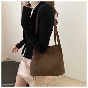 Detail view of brown corduroy shoulder bag featuring embroidered strawberry patterns