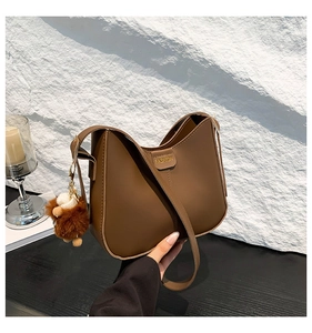 Detailed view of brown retro leather bucket bag with fashion tag and plush animal charm