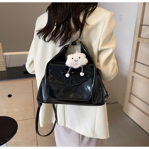 Detail of black glossy tote bag featuring a bow design and a white plush cloud charm