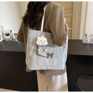 Silver metallic tote bag with ruffle texture, butterfly buckle, and cloud charm on model