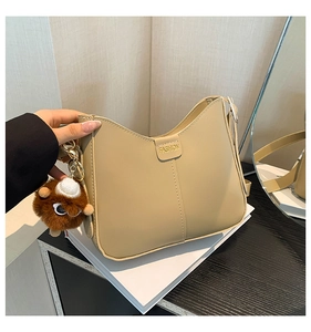 Detail of beige hobo bag showing fashion embossing, vertical stitching, and plush charm