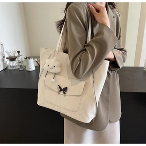 Detail of cream tote bag with butterfly clasp and fluffy cloud pendant charm