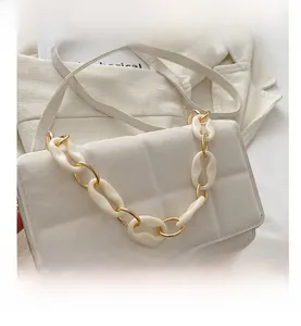 Detailed shot of white quilted leather texture and gold chain on the square crossbody bag