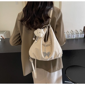 Detail of off-white pleated tote bag with silver chain and plush cloud charm on shoulder