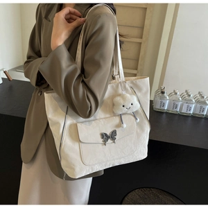 Detailed view of white tote bag with silver butterfly buckle and cloud plush charm