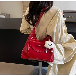 Detail of red patent leather tote bag with a bow and a white plush cloud keychain charm