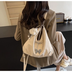 Detail of off-white hobo bag with silver butterfly charm and cloud plush on a model