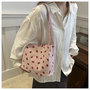 Close-up of pink corduroy shoulder bag with strawberry print and leather straps