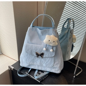 Detail of light blue textured shoulder bag with silver butterfly buckle and cloud charm